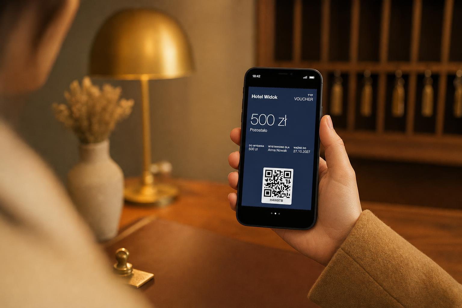 Gość pokazuje w recepcji hotelu voucher w telefonie